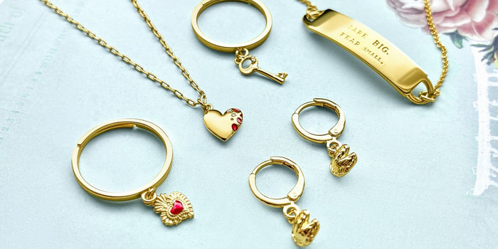 Fortune & Frame dainty jewelry including rings, a necklace, and a bracelet, on a green background.
